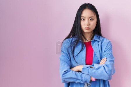 Téléchargez les photos : Jeune femme asiatique debout sur fond rose sceptique et nerveux, expression désapprobatrice sur le visage avec les bras croisés. personne négative. - en image libre de droit