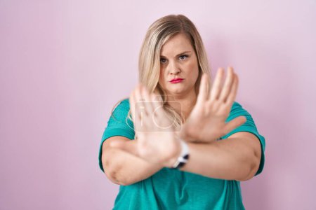 Foto de Caucásico más tamaño mujer de pie sobre fondo rosa rechazo expresión cruzando brazos y palmas haciendo signo negativo, cara enojada - Imagen libre de derechos