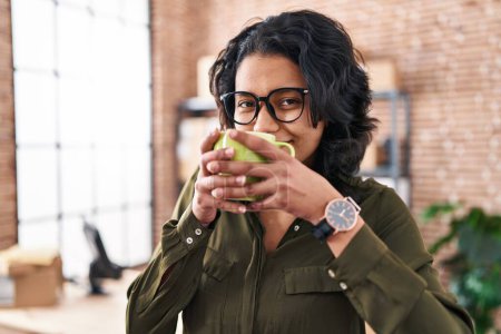 Téléchargez les photos : Young latin woman ecommerce business worker drinking coffee at office - en image libre de droit