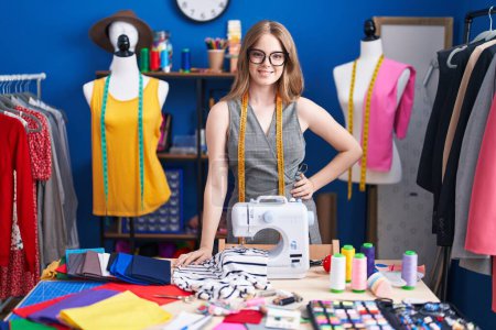 Téléchargez les photos : Jeune femme tailleur souriant confiance debout à l'usine de vêtements - en image libre de droit