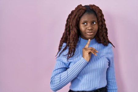 Photo for African woman standing over pink background thinking concentrated about doubt with finger on chin and looking up wondering - Royalty Free Image