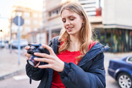 Téléchargez les photos : Jeune femme blonde souriant confiant en utilisant une caméra professionnelle à la rue - en image libre de droit