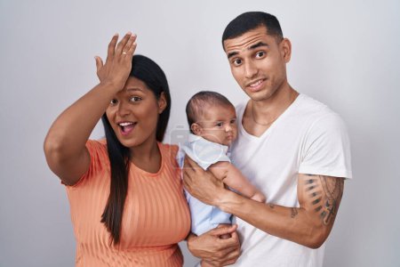 Photo for Young hispanic couple with baby standing together over isolated background surprised with hand on head for mistake, remember error. forgot, bad memory concept. - Royalty Free Image