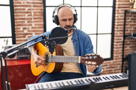 Photo for Young bald man musician playing classical guitar at music studio - Royalty Free Image