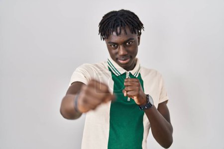 Photo for African man with dreadlocks standing over isolated background punching fist to fight, aggressive and angry attack, threat and violence - Royalty Free Image
