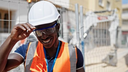 Téléchargez les photos : Homme afro-américain constructeur souriant confiance debout sur le lieu de construction - en image libre de droit