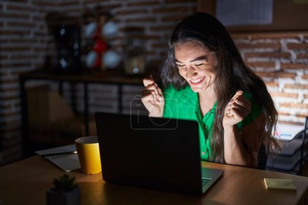 Photo for Young teenager girl working at the office at night excited for success with arms raised and eyes closed celebrating victory smiling. winner concept. - Royalty Free Image