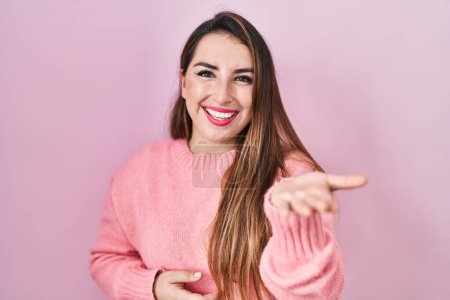 Téléchargez les photos : Jeune femme hispanique debout sur fond rose souriant joyeuse offrant main de paume donnant assistance et acceptation. - en image libre de droit