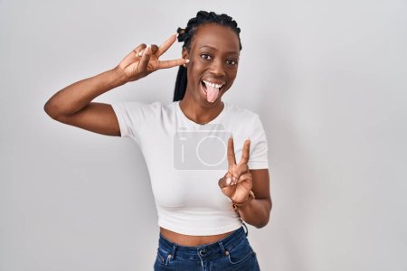 Photo for Beautiful black woman standing over isolated background smiling with tongue out showing fingers of both hands doing victory sign. number two. - Royalty Free Image