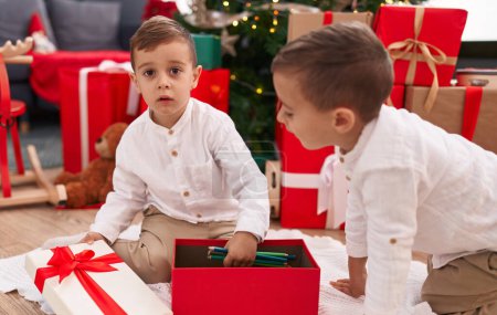 Foto de Adorables chicos celebrando la Navidad desempacando lápices de regalo en casa - Imagen libre de derechos