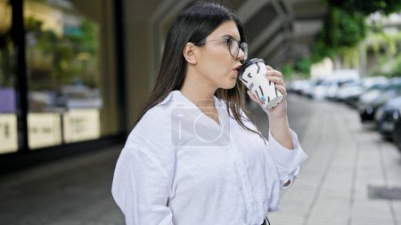 Foto de Joven mujer hispana hermosa bebiendo tomar café en las calles de Madrid - Imagen libre de derechos