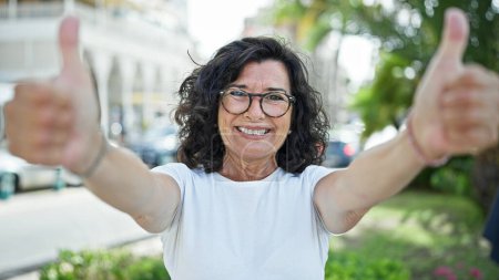 Photo for Middle age hispanic woman smiling confident doing ok sign with thumbs up at park - Royalty Free Image