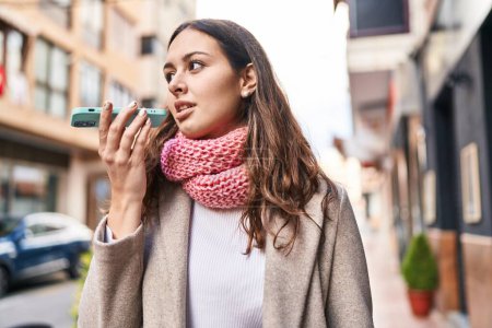 Téléchargez les photos : Young beautiful hispanic woman talking on smartphone wearing scarf at street - en image libre de droit