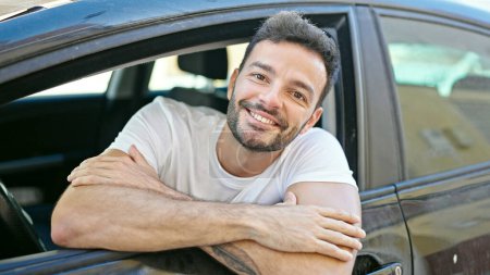 Photo for Young hispanic man smiling confident sitting on car at street - Royalty Free Image