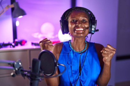 Photo for African woman with dreadlocks wearing headphones screaming proud, celebrating victory and success very excited with raised arms - Royalty Free Image