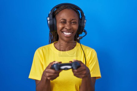 Photo for African american woman playing video games winking looking at the camera with sexy expression, cheerful and happy face. - Royalty Free Image