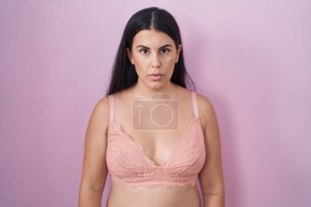 Photo for Young hispanic woman wearing pink bra relaxed with serious expression on face. simple and natural looking at the camera. - Royalty Free Image