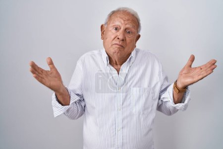 Photo for Senior man with grey hair standing over isolated background clueless and confused expression with arms and hands raised. doubt concept. - Royalty Free Image