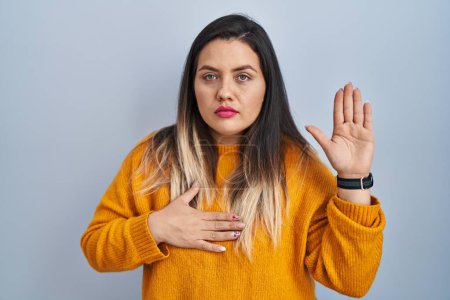 Téléchargez les photos : Young hispanic woman standing over isolated background swearing with hand on chest and open palm, making a loyalty promise oath - en image libre de droit