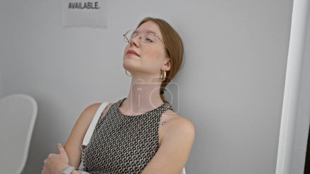 Téléchargez les photos : Jeune femme blonde assise sur une chaise détendue dans la salle d'attente - en image libre de droit