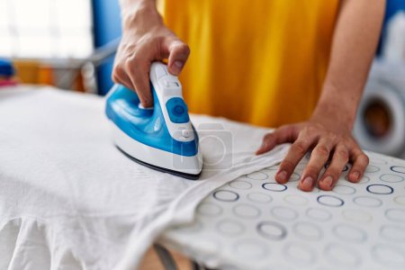 Foto de Joven hombre rubio planchando ropa en la lavandería - Imagen libre de derechos