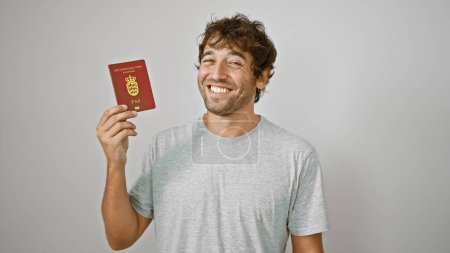 Téléchargez les photos : Joyeux jeune homme passe avec confiance son passeport danois avec un sourire, isolé sur fond blanc. un voyageur décontracté et heureux du Danemark, prêt pour son aventure européenne. - en image libre de droit