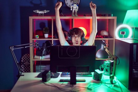 Photo for Young blond man streamer playing video game with winner expression at gaming room - Royalty Free Image