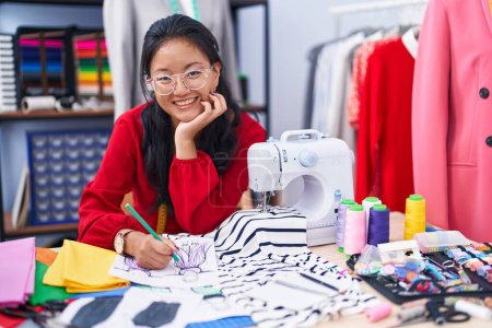 Photo for Young chinese woman tailor smiling confident drawing clothing design at atelier - Royalty Free Image