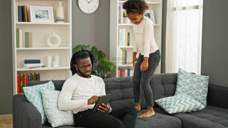 Foto de Afro-americanos padre e hija sentado en sofá trabajo mientras niño molestar en casa - Imagen libre de derechos