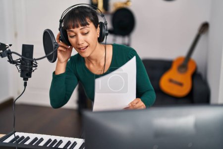 Téléchargez les photos : Jeune belle musicienne hispanique souriante chanson de chant confiante au studio de musique - en image libre de droit