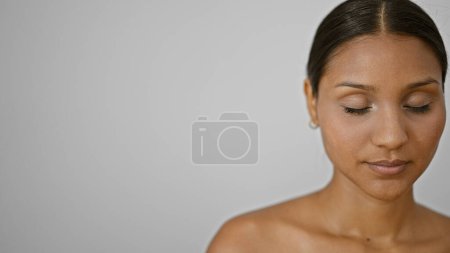 Téléchargez les photos : Jeune femme latine debout avec un visage sérieux et les yeux fermés sur fond blanc isolé - en image libre de droit
