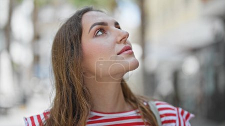 Photo for Young blonde woman looking to the sky with relaxed expression at street - Royalty Free Image