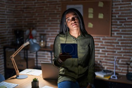 Photo for Young african american with braids working at the office at night looking sleepy and tired, exhausted for fatigue and hangover, lazy eyes in the morning. - Royalty Free Image