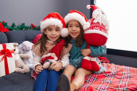 Photo for Adorable girls sitting on sofa celebrating christmas at home - Royalty Free Image