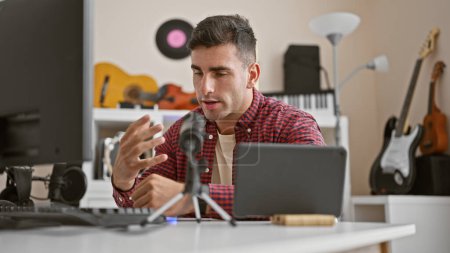Téléchargez les photos : Young hispanic man radio reporter using microphone speaking at radio studio - en image libre de droit