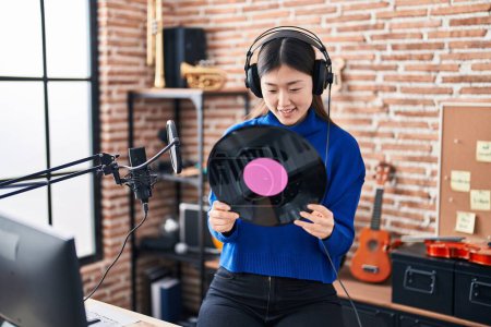 Téléchargez les photos : Femme artiste chinoise souriant confiant tenant disque vinyle au studio de musique - en image libre de droit