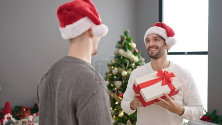 Photo for Two men couple celebrating christmas holding gift at home - Royalty Free Image