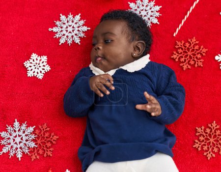 Téléchargez les photos : Bébé afro-américain couché sur le sol avec décor de Noël à la maison - en image libre de droit
