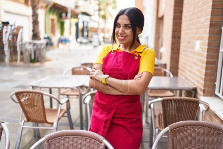 Photo for Young beautiful arab woman waitress smiling confident standing with arms crossed gesture at coffee shop terrace - Royalty Free Image