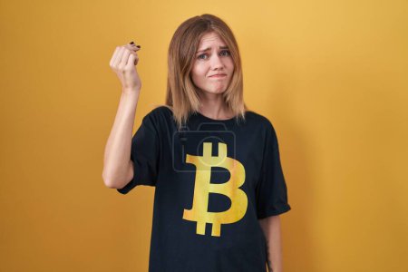 Téléchargez les photos : Blonde femme caucasienne portant Bitcoin t-shirt faire geste italien avec la main et les doigts expression confiante - en image libre de droit