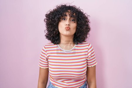 Photo for Young middle east woman standing over pink background looking at the camera blowing a kiss on air being lovely and sexy. love expression. - Royalty Free Image