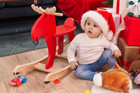 Téléchargez les photos : Adorable bébé caucasien assis sur le sol par des cadeaux de Noël à la maison - en image libre de droit