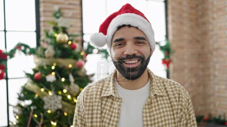Foto de Joven hombre hispano sonriendo celebrando la Navidad en casa - Imagen libre de derechos