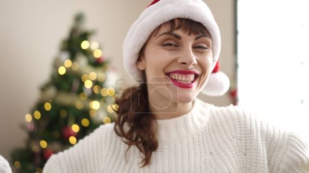 Téléchargez les photos : Jeune femme caucasienne souriante portant un chapeau de Noël à la maison - en image libre de droit