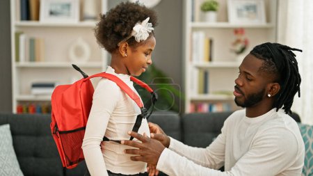 Téléchargez les photos : Père et fille afro-américains portant un sac à dos se préparant à aller à l'école à la maison - en image libre de droit
