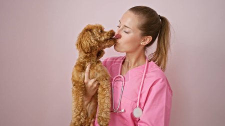 Téléchargez les photos : Jeune femme caucasienne avec chien vétérinaire souriant confiant tenant chien embrassant sur fond rose isolé - en image libre de droit