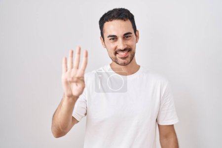 Téléchargez les photos : Bel homme hispanique debout sur fond blanc montrant et pointant vers le haut avec les doigts numéro quatre tout en souriant confiant et heureux. - en image libre de droit