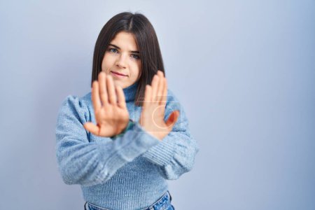 Téléchargez les photos : Jeune femme hispanique debout sur fond bleu expression de rejet croisant les bras et les paumes faisant signe négatif, visage en colère - en image libre de droit