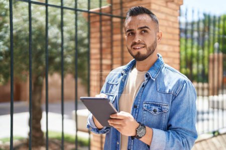 Téléchargez les photos : Young hispanic man smiling confident using touchpad at street - en image libre de droit