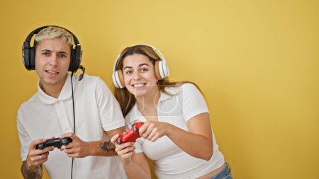 Foto de Hermosa pareja jugando videojuego sonriendo sobre fondo amarillo aislado - Imagen libre de derechos